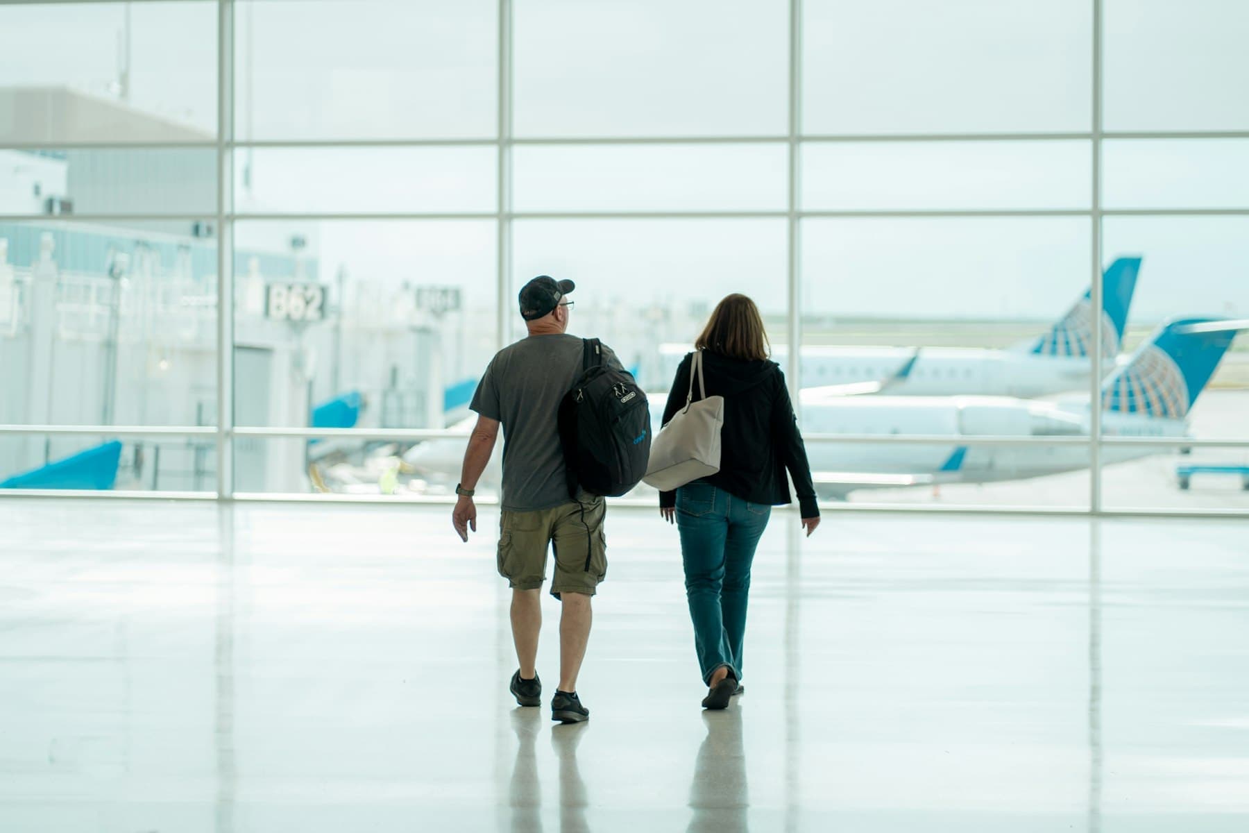 Two travellers walking through a bright airport terminal