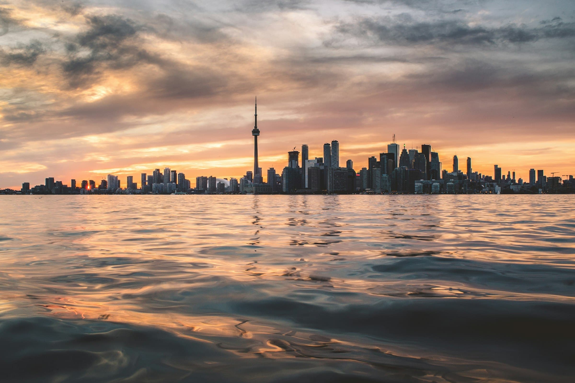 The Toronto skyline and CN Tower across Lake Ontario at sunset